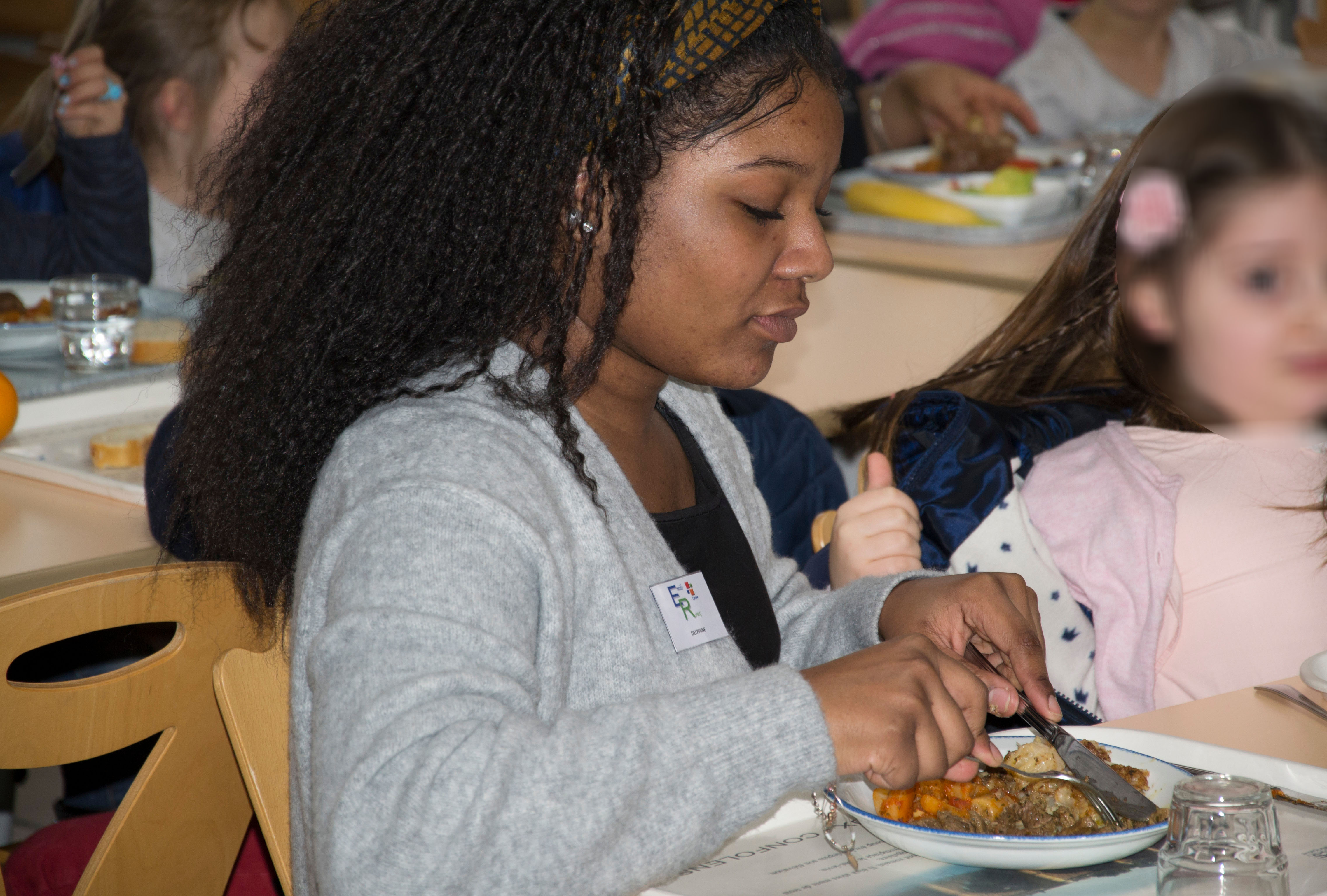 Une élève d'ASSP aidant une enfant à couper sa viande.